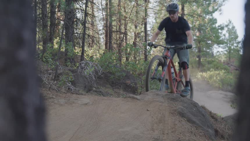 Man rides a bike and jumps over the forest track in the woods