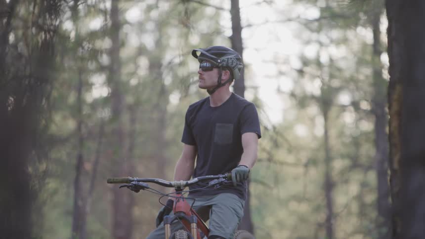 A young man sits on a mountain bike and looks around the forest he is in
