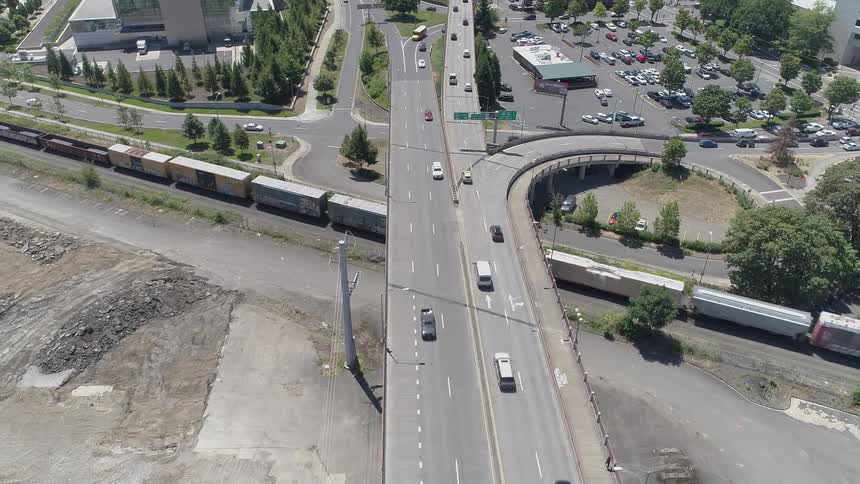 Vehicles and a train pass through an intersection and overpass highway