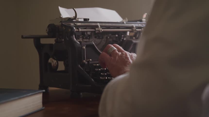 A person wearing a large ring types on an old fashioned typewriter