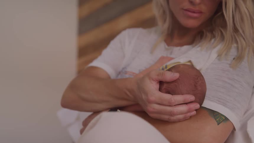A blonde haired mother caresses her newborn baby