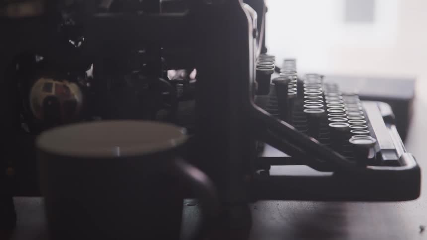 Vintage typewriter on desk near cup of hot beverage