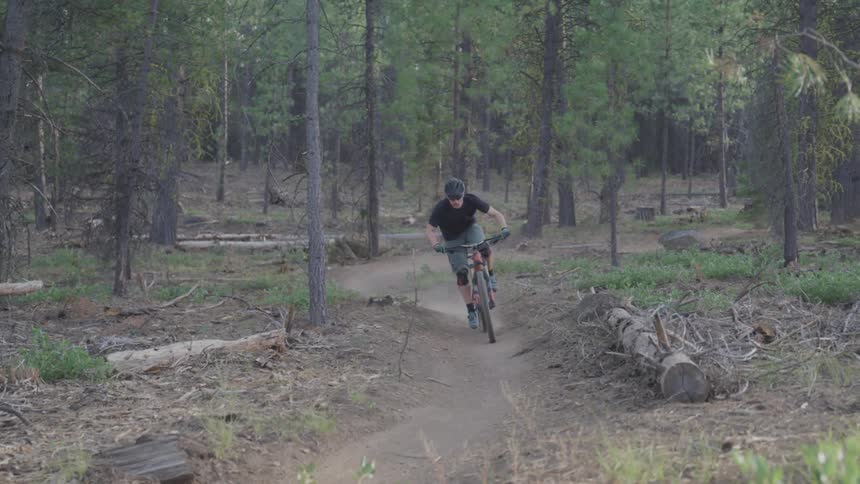 A man is riding his bicycle on the dirt path