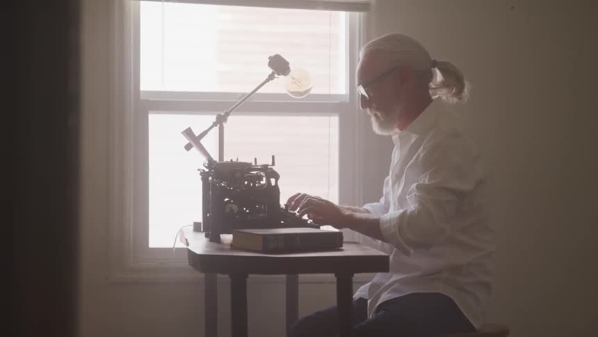 An old man typing on the room