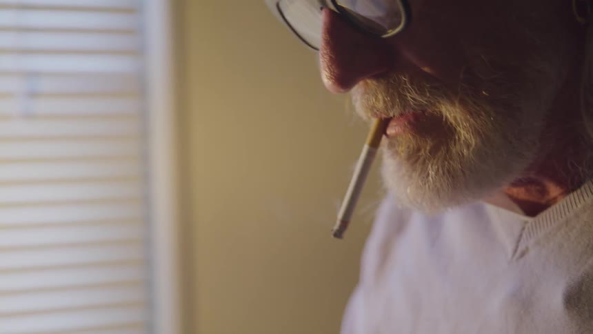 An elderly man smoke at the room