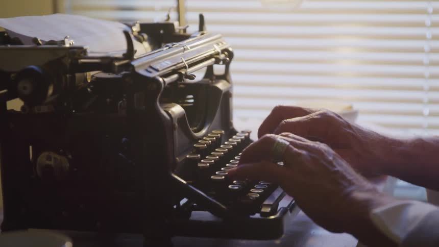 An old man hand typing on an old type machine