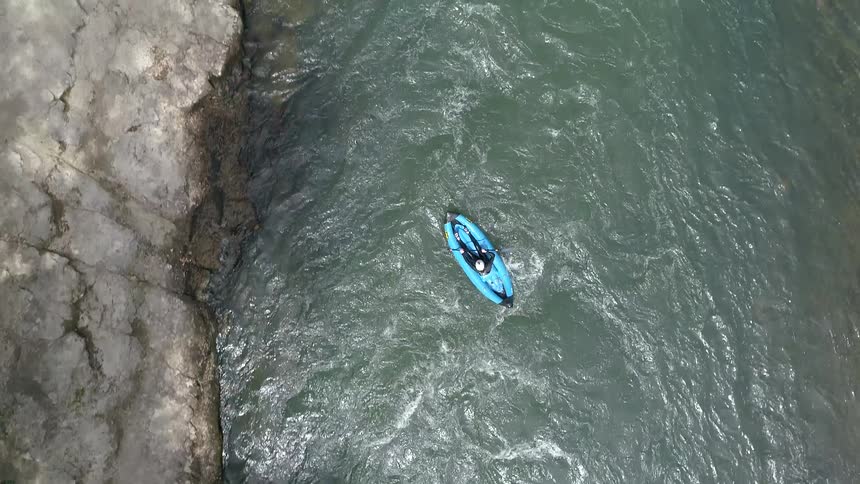 Aerial of a kayak paddling down a strong current in a river