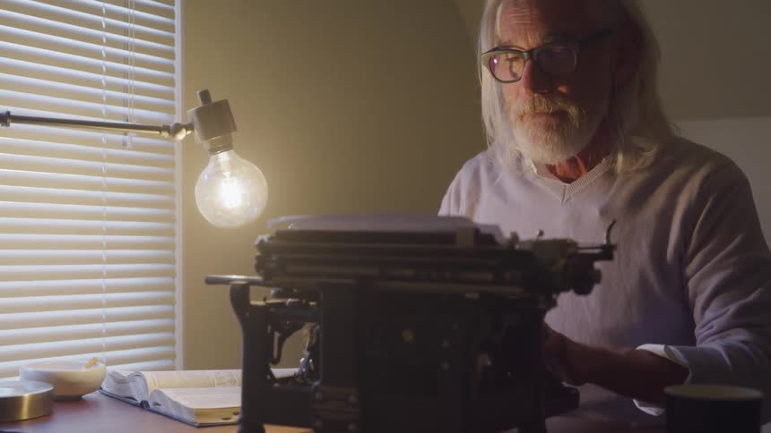 A man is typing on a typewriter indoors