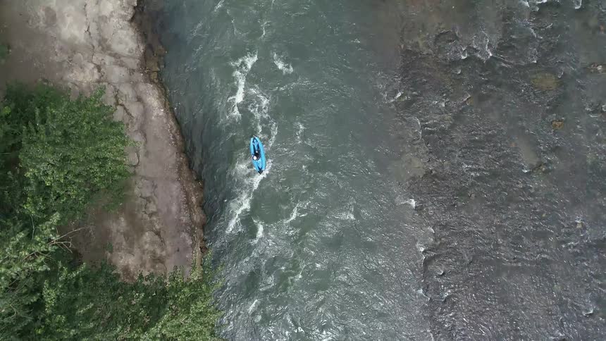 A person paddles a kayak down a river