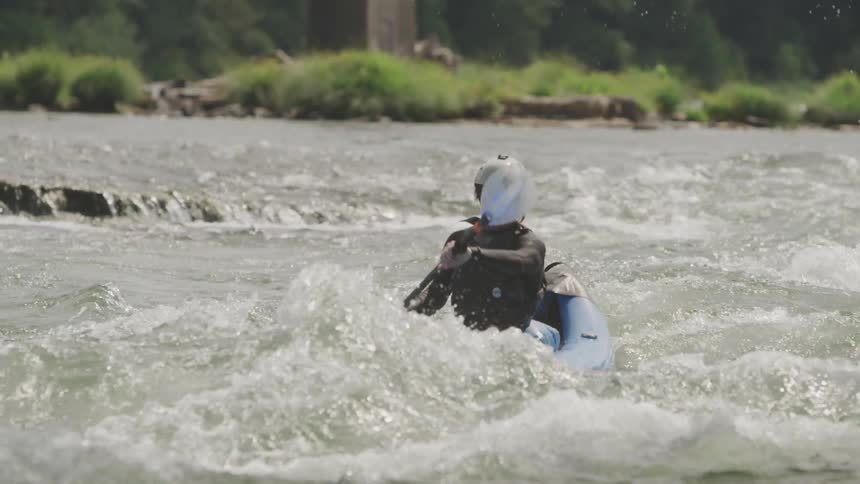 A young man kayaks in a rough river