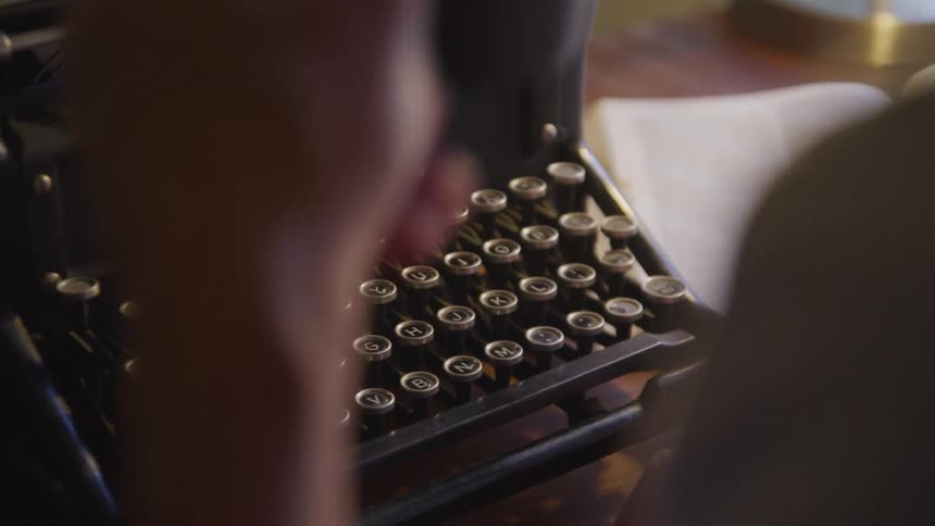 Man drinks coffee before typing on the typewriter in a room