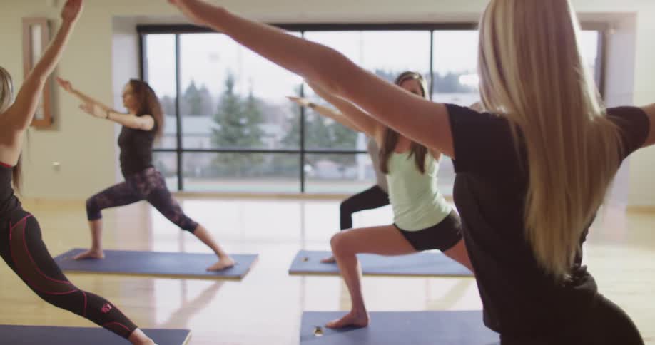 Young women perform yoga in a studio during the day