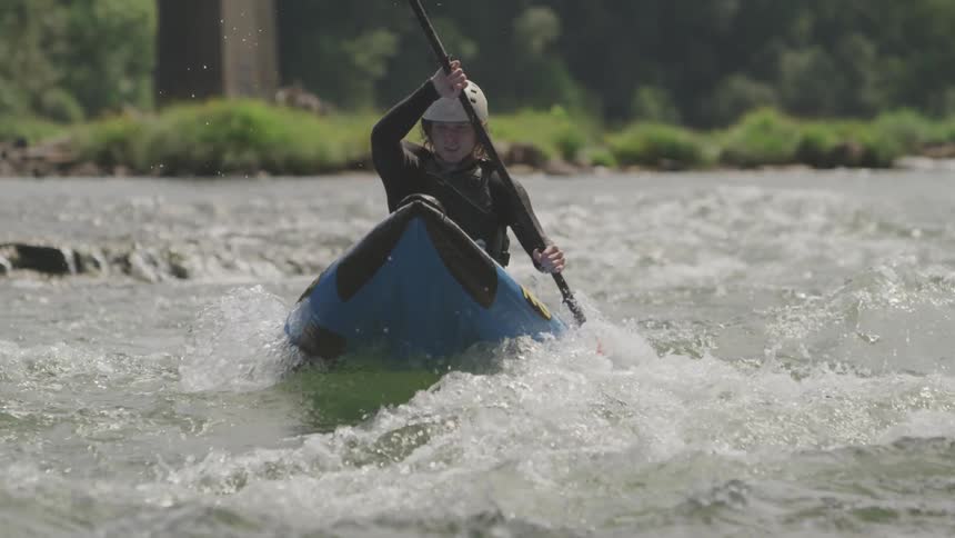 A man skillfully paddles his kayak along a swiftly flowing and turbulent river