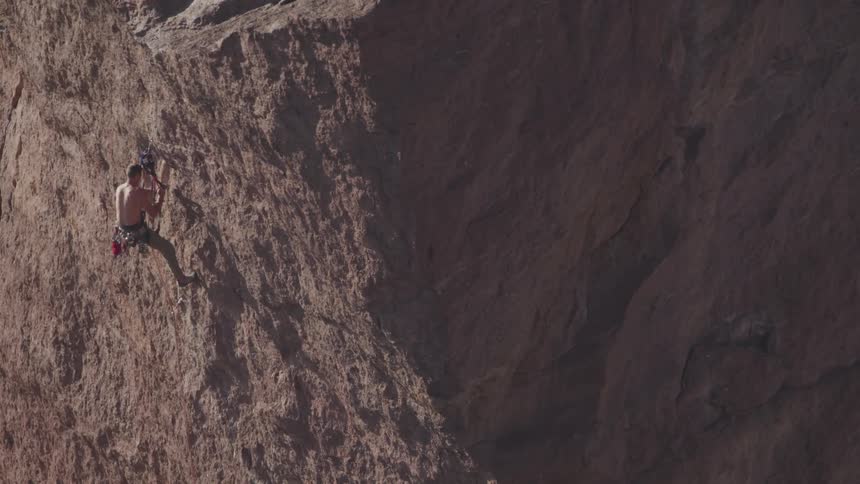 Rock climber climbing down from the face of a cliff