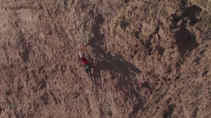 Aerial view of man climbing mountain cliff
