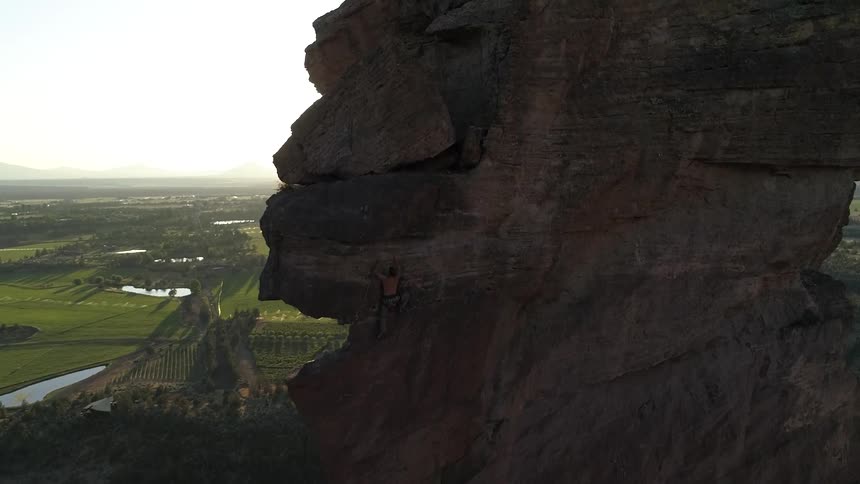 A sheer faced rock formation shoots up into the sky in the countryside at dawn
