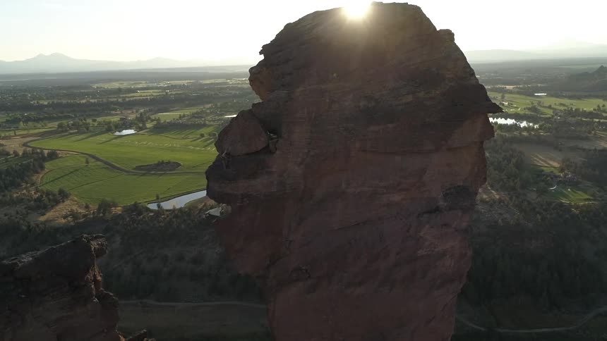 A tall rock formation stands beside the grasslands and open terrain