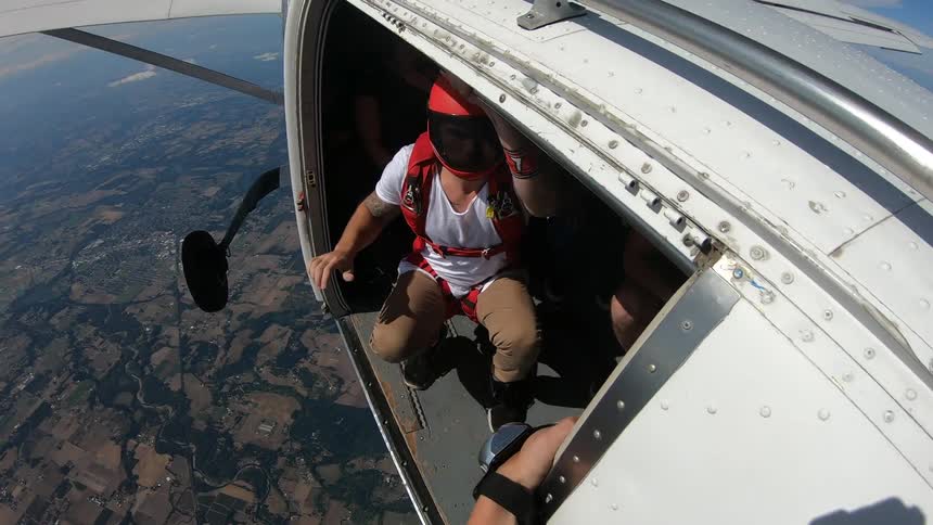 Person climbing outside of a plane in the air before jumping