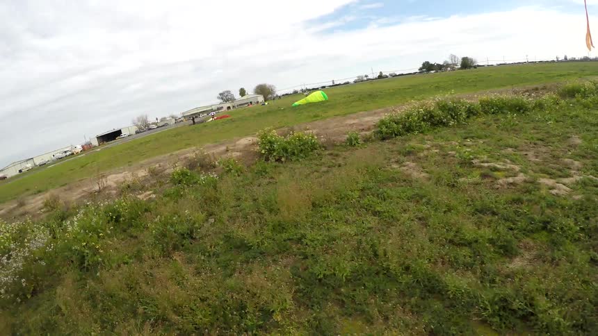 A woman lands a parachute and runs along the ground with it