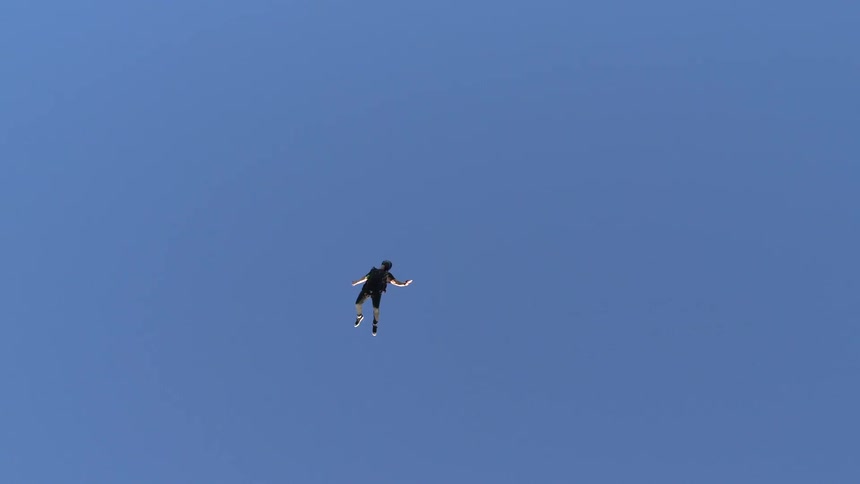 Person free falls in clear blue sky