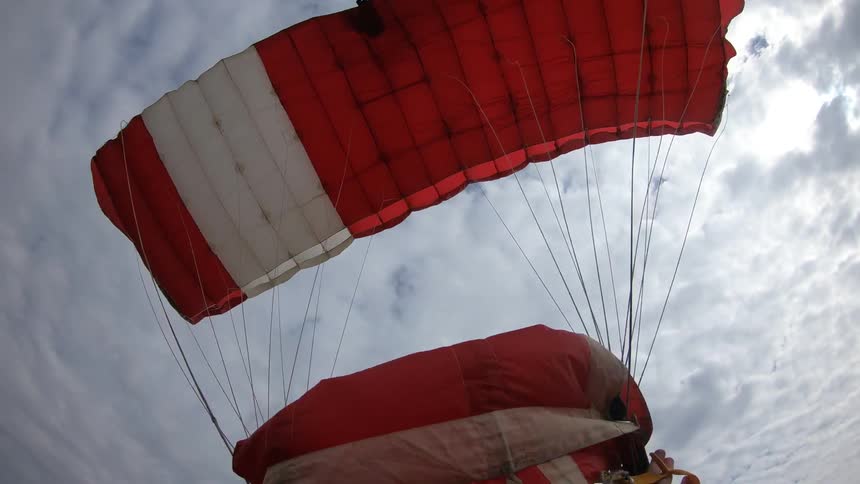 Parachute jumpers land in a grass field
