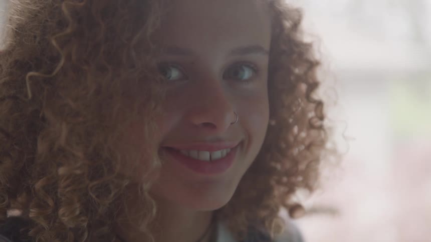 A woman with curly red hair smiles into the camera
