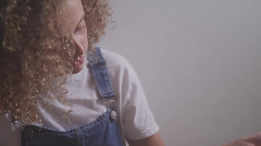 Curly red hair girl sitting on the ground plays a guitar in a room