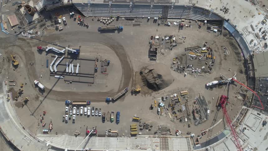 Construction crew and vehicles work inside a stadium
