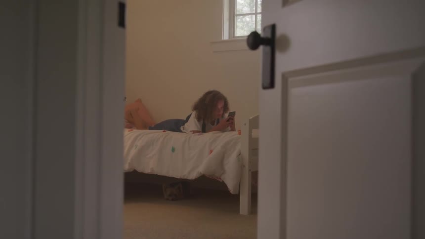 A woman play with her phone at the bedroom