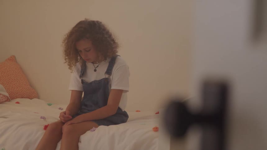 Woman sits downhearted on side of bed