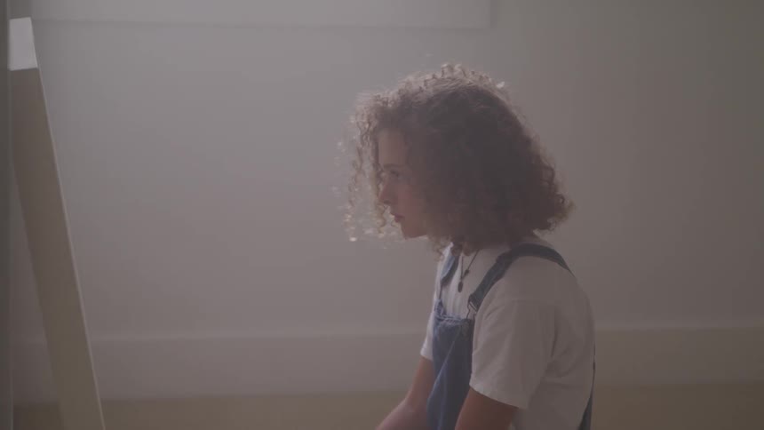 A young girls sits inside and looks in a mirror