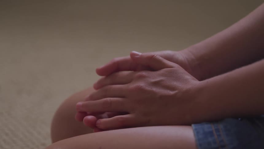 A person sits with their hands in their lap