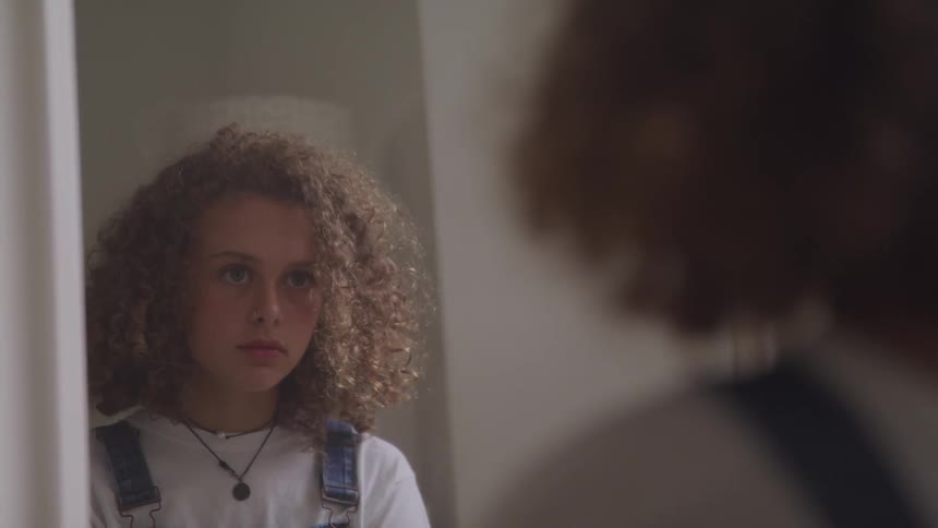 A young girls looks in a mirror
