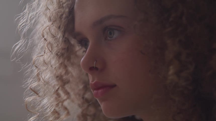 Curly red hair girl raises her head during daylight
