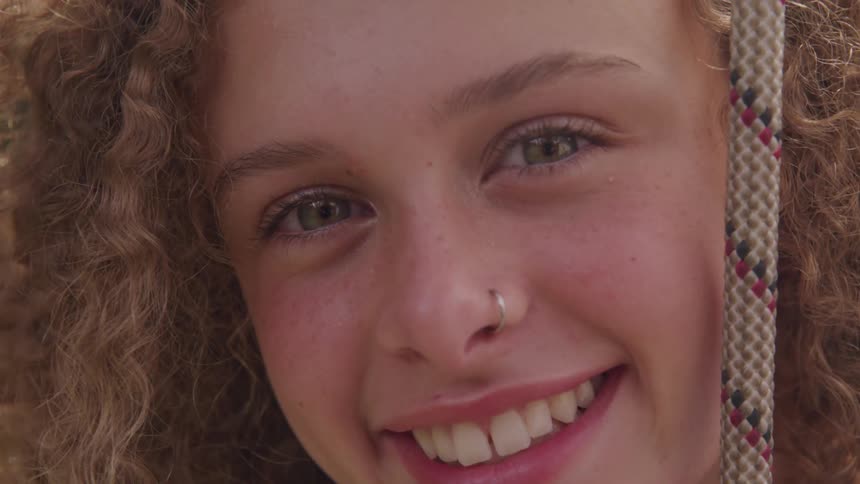 Curly red hair girl wearing nose ring looks at the camera and smiles