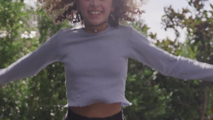 A curly woman jumping happily