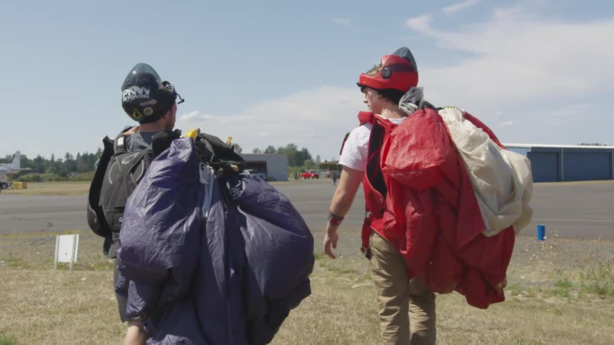 Two men walk and carry parachutes