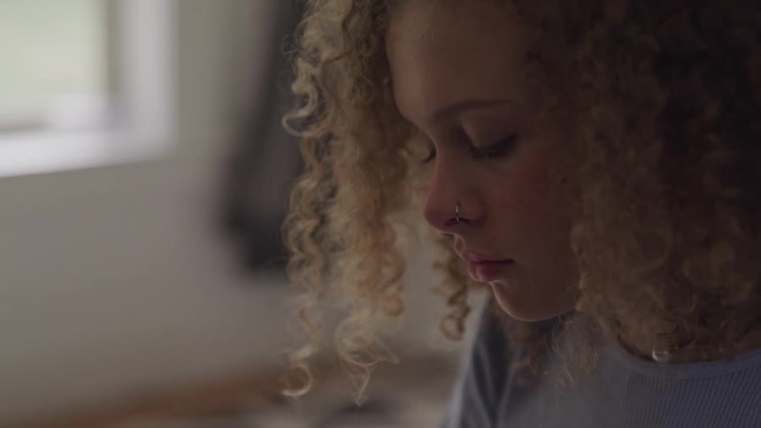 Curly red hair girl wearing nose ring plays the piano in a room