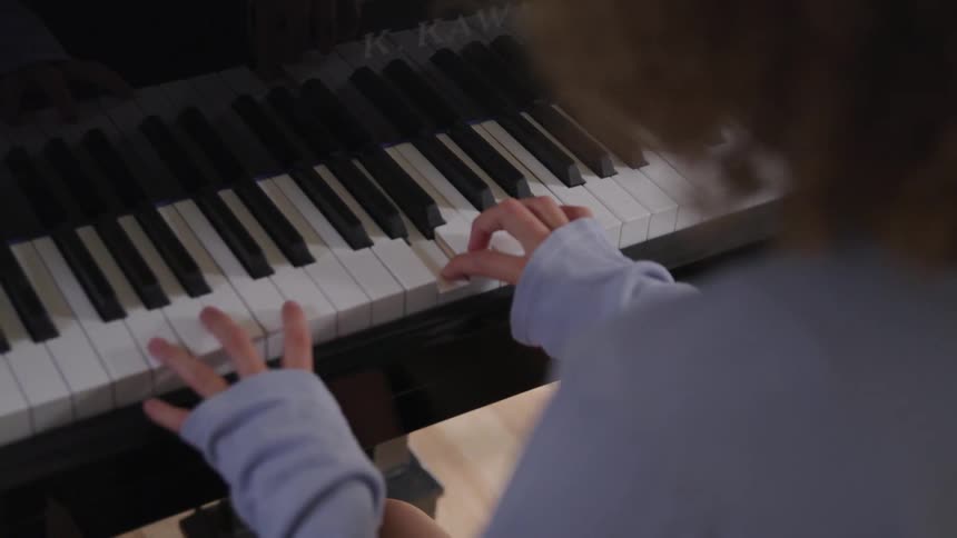 Girl plays the piano indoors during daylight