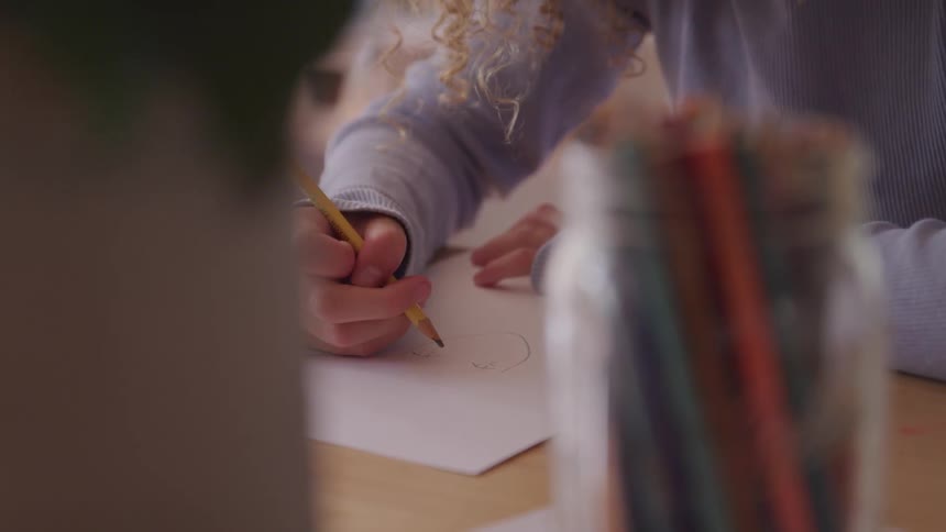 A young girl draws on a paper