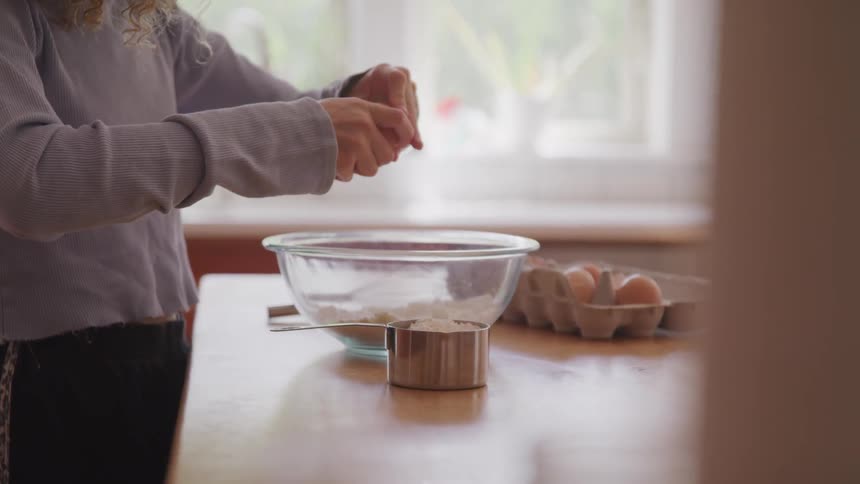 Girl cracks egg in the kitchen