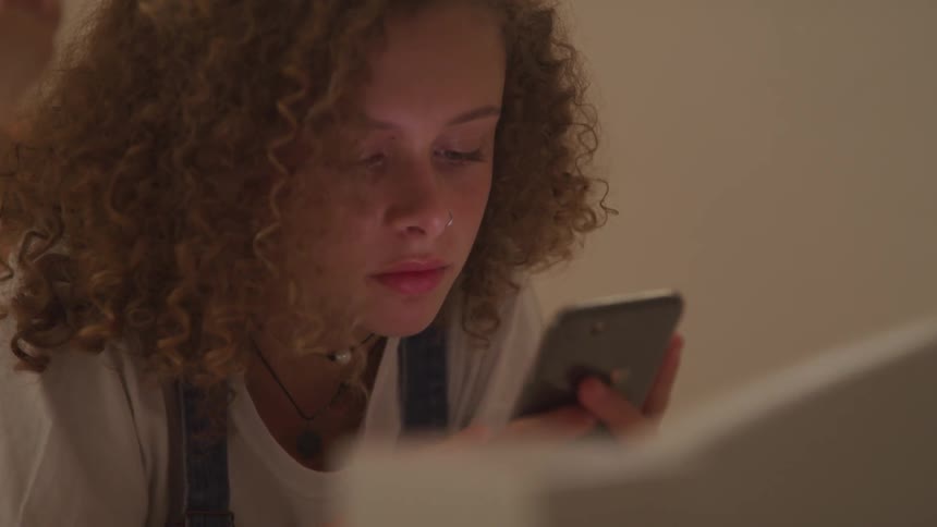 Young girl looking intently at her phone and swiping her thumb across the screen
