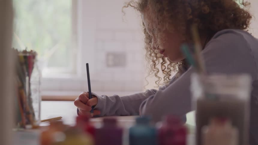 A little girls sits and draws on a piece of paper