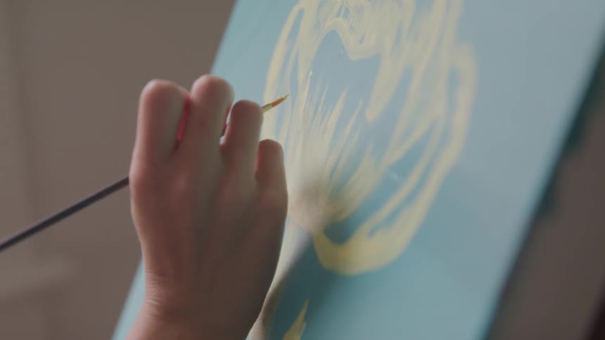 A woman hand painting at the canvas
