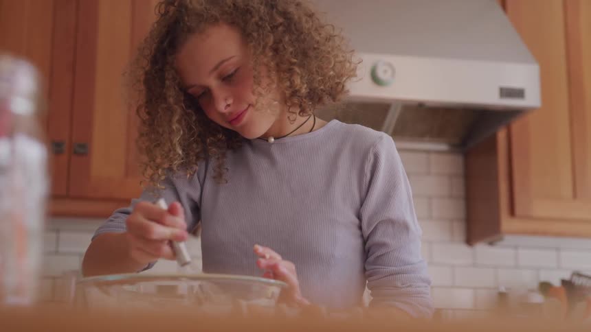 A curly female cooking at the kitchen