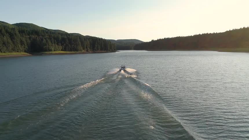 Aerial view of man practicing water ski on lake near mountains