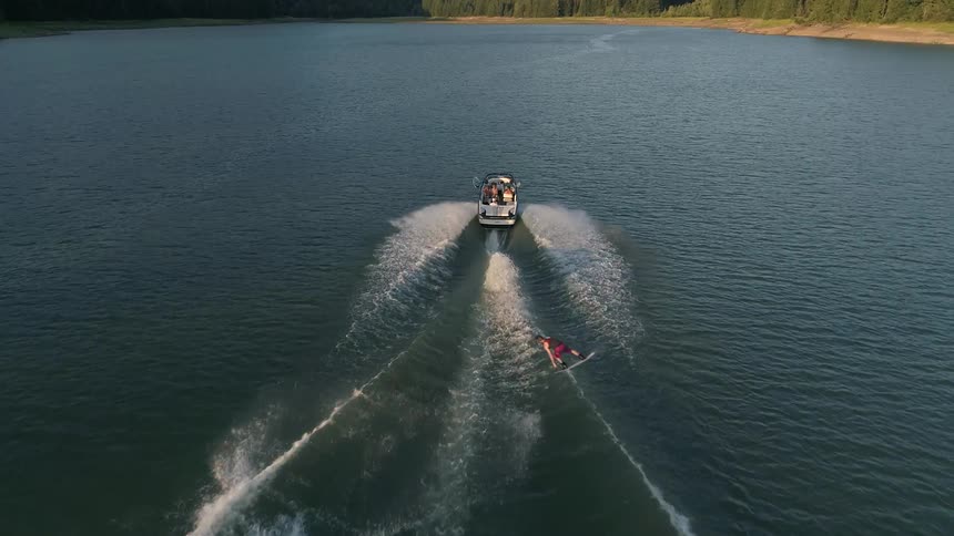 Man water skiing and jumping the waves created by the boat pulling him