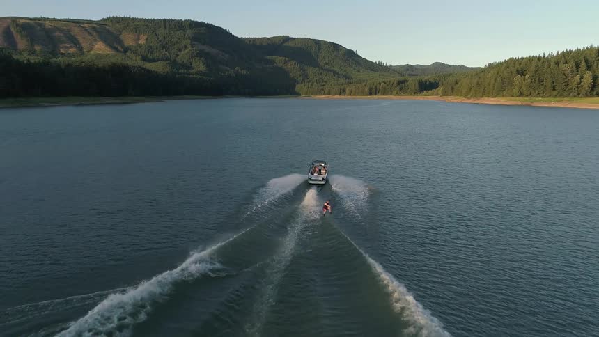A water skier jumps over the boats wake and splashes down