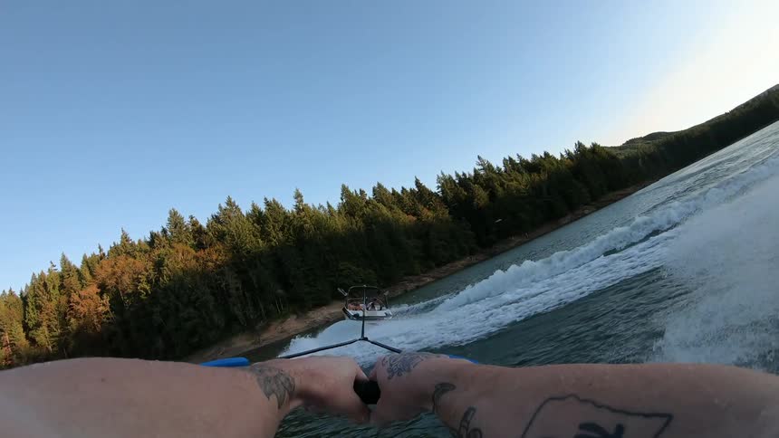 First person view of man doing water ski on lake at sunset
