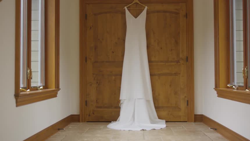 A white wedding gown hangs from the top of tall wooden cupboard doors